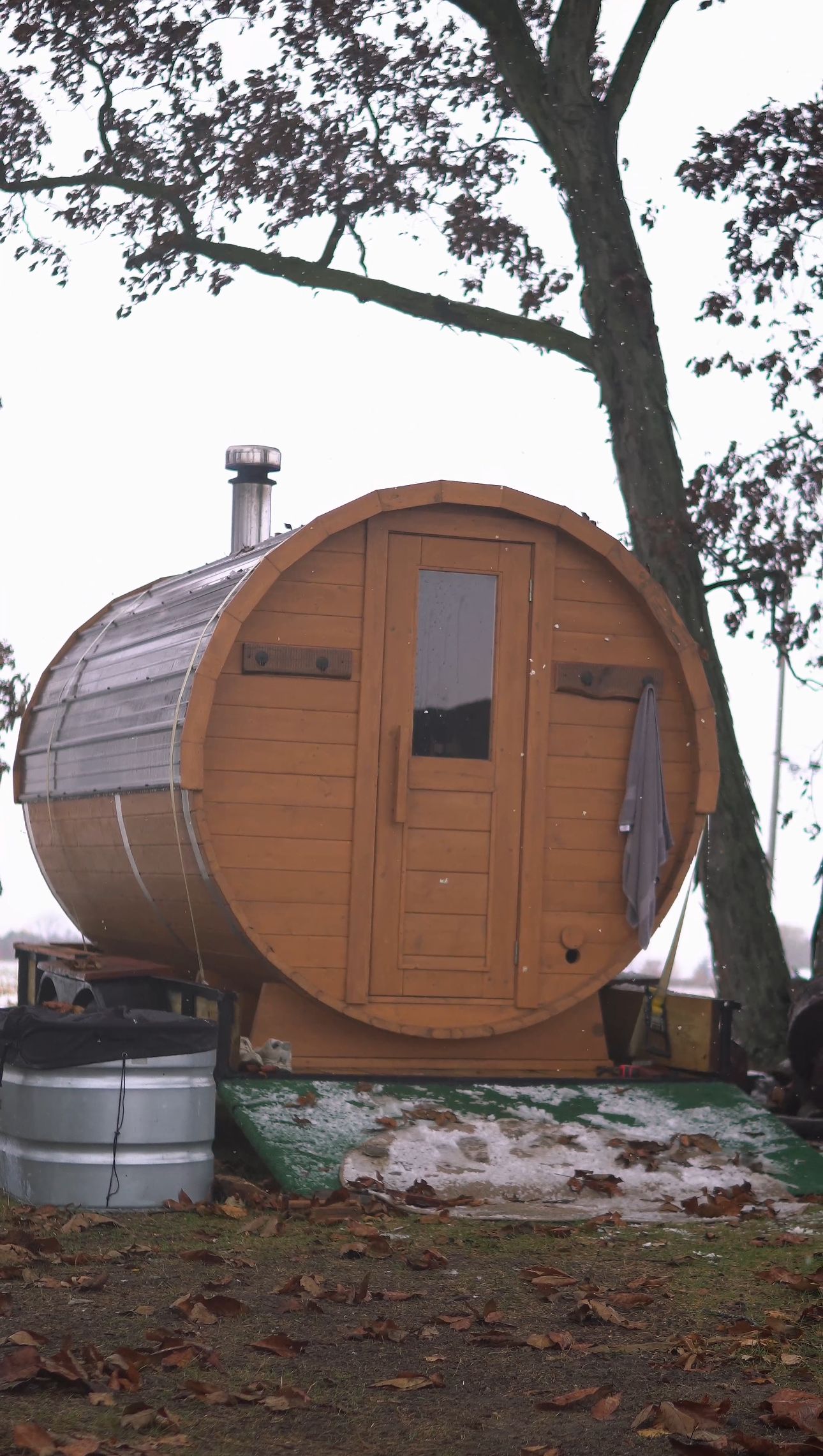 The NFinite sauna set up under a tree in a backyard, cold plunge tub beside it